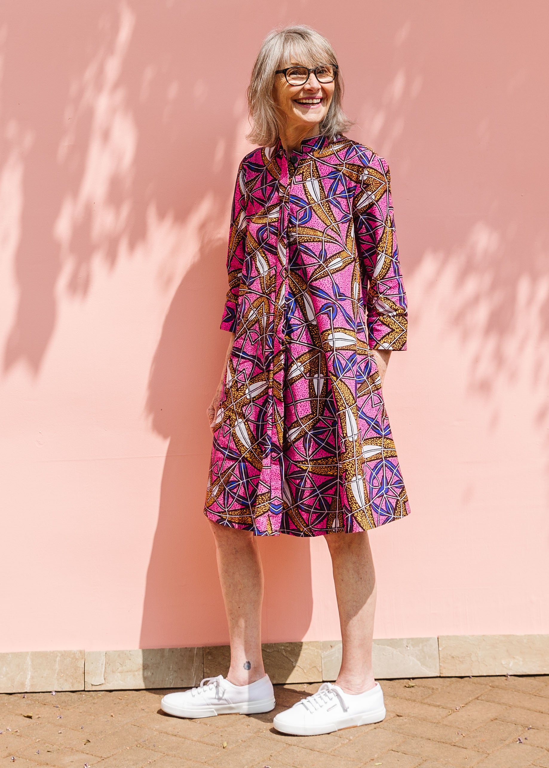 Model wearing a pink dress with floral yellow, blue and white print.