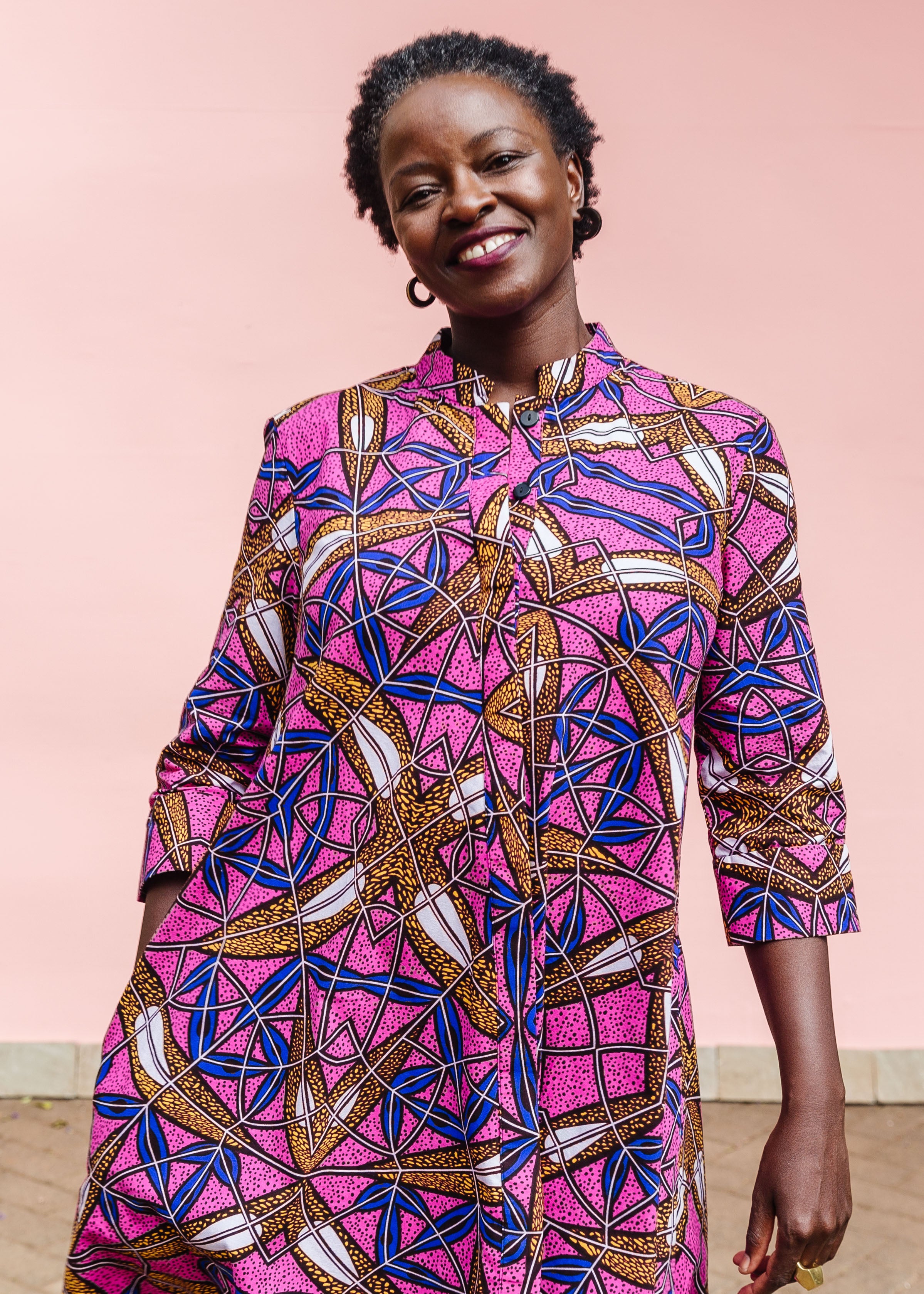 Model wearing a pink dress with floral yellow, blue and white print.