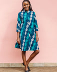 Model wearing circular grid print dress, with hues of blue.