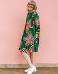 Model wearing green dress with brown and yellow star print.