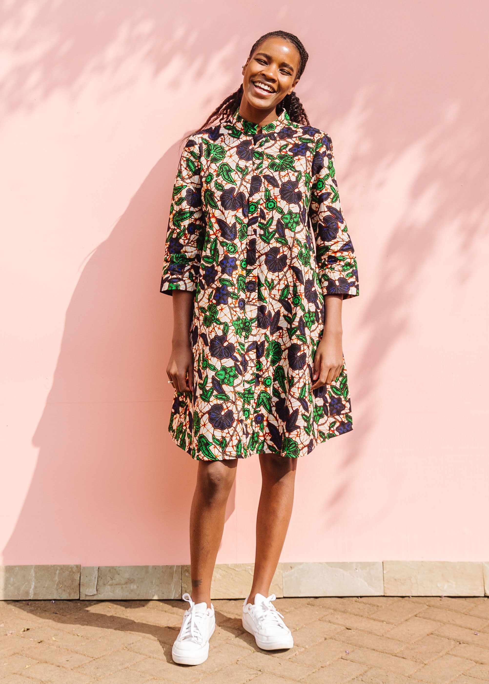 Model wearing brown dress with green and blue vine print.