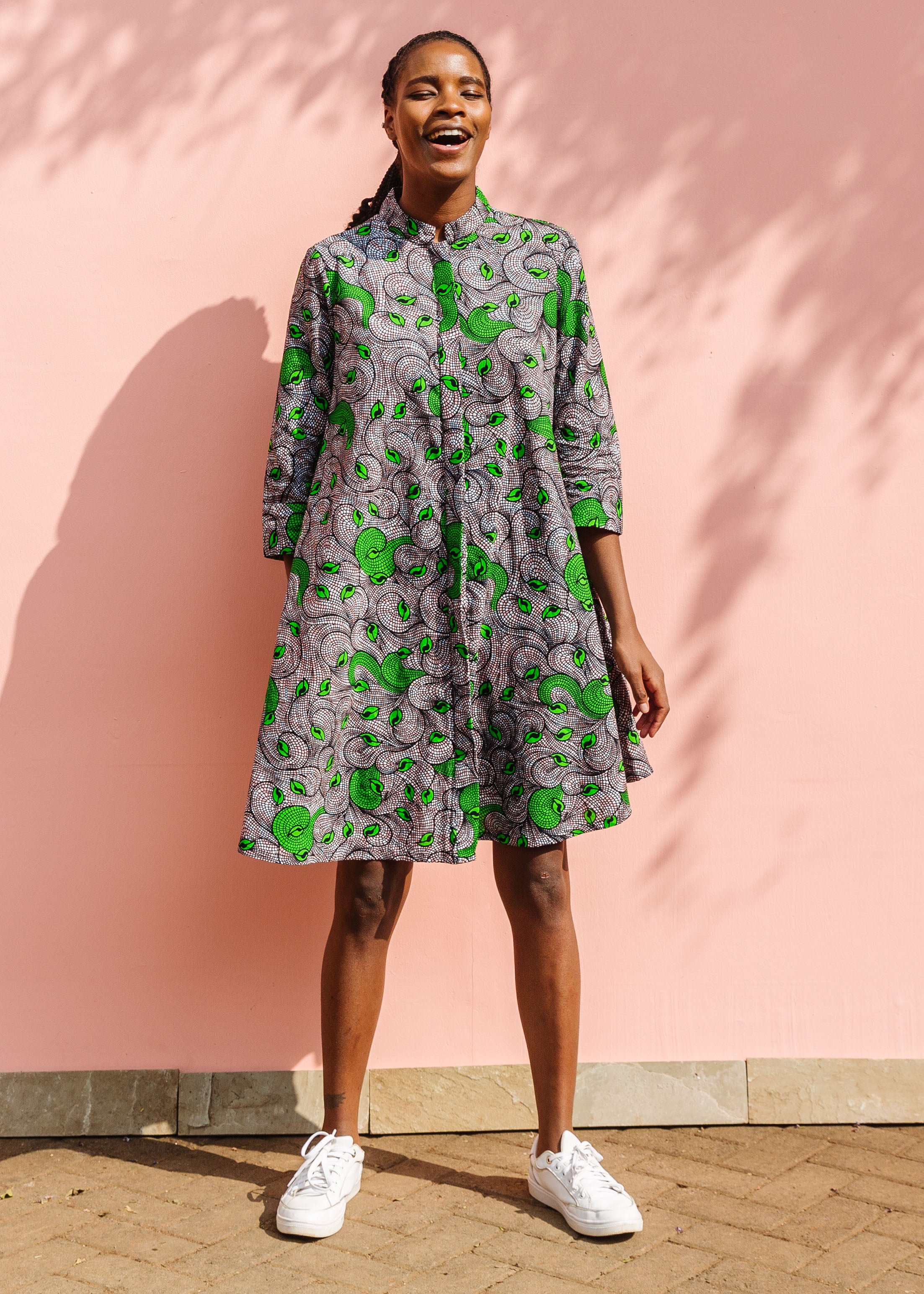 Model wearing white and black dress with green swirls.