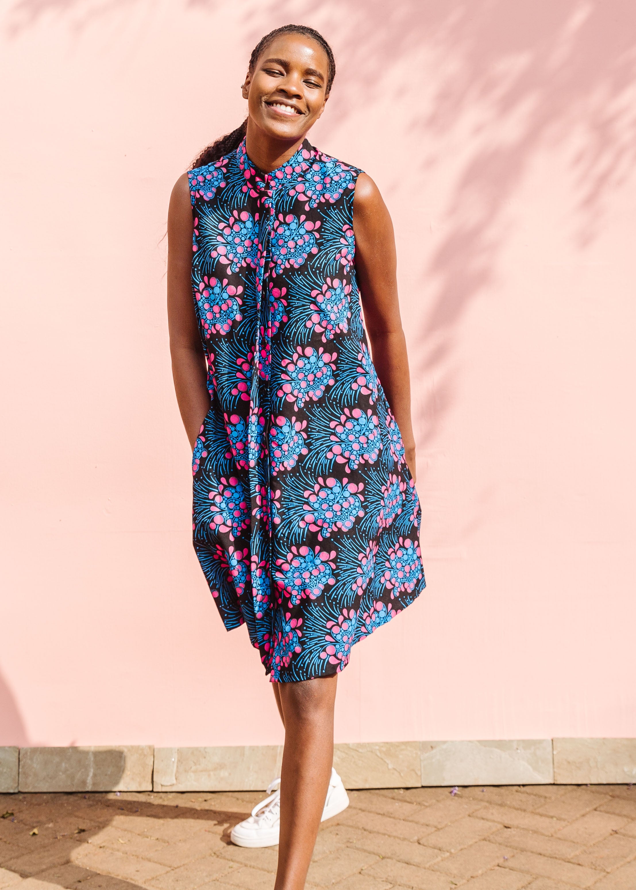 Model wearing black sleeveless dress with blue and pink poppy print.