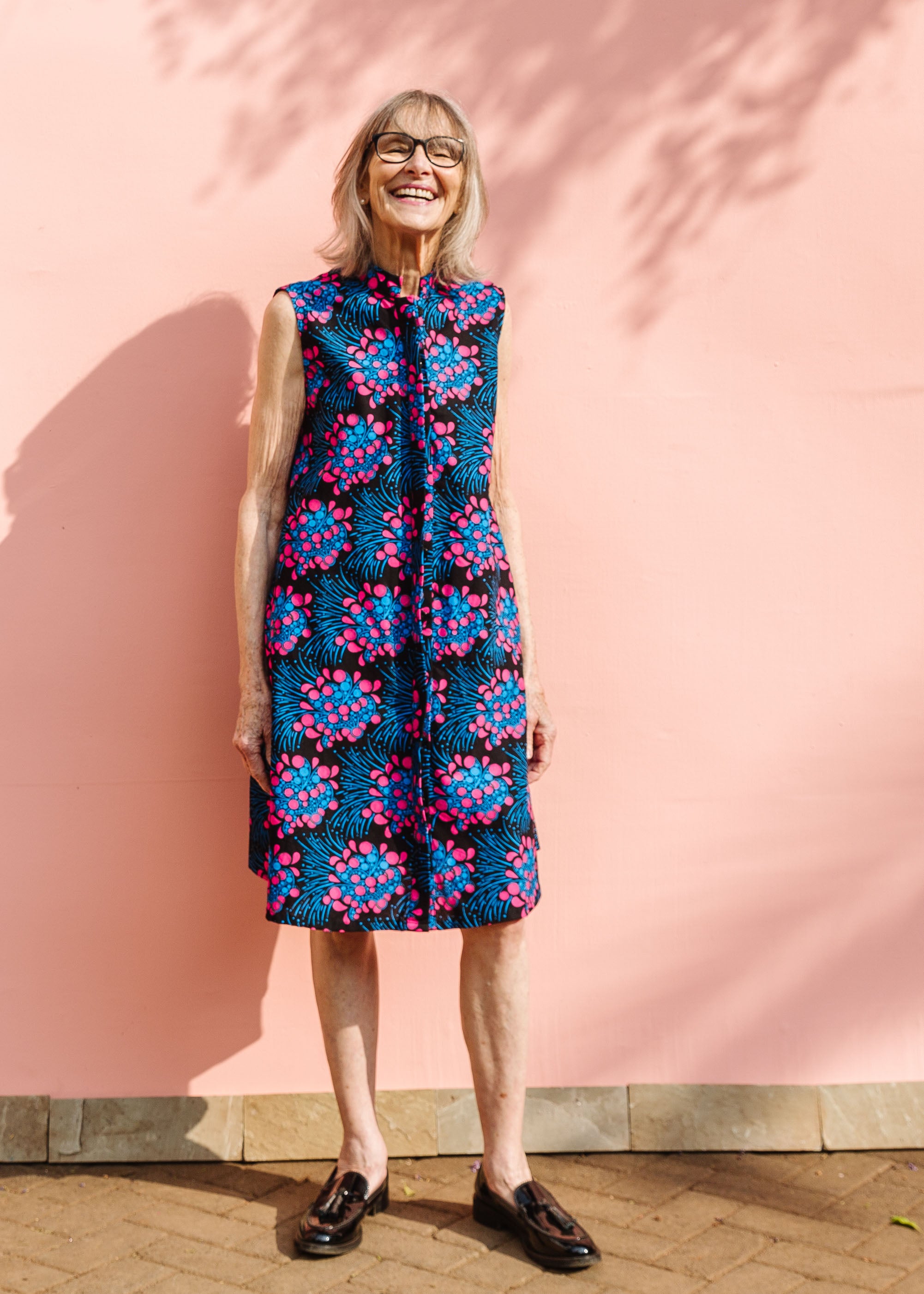 Model wearing black sleeveless dress with blue and pink poppy print.