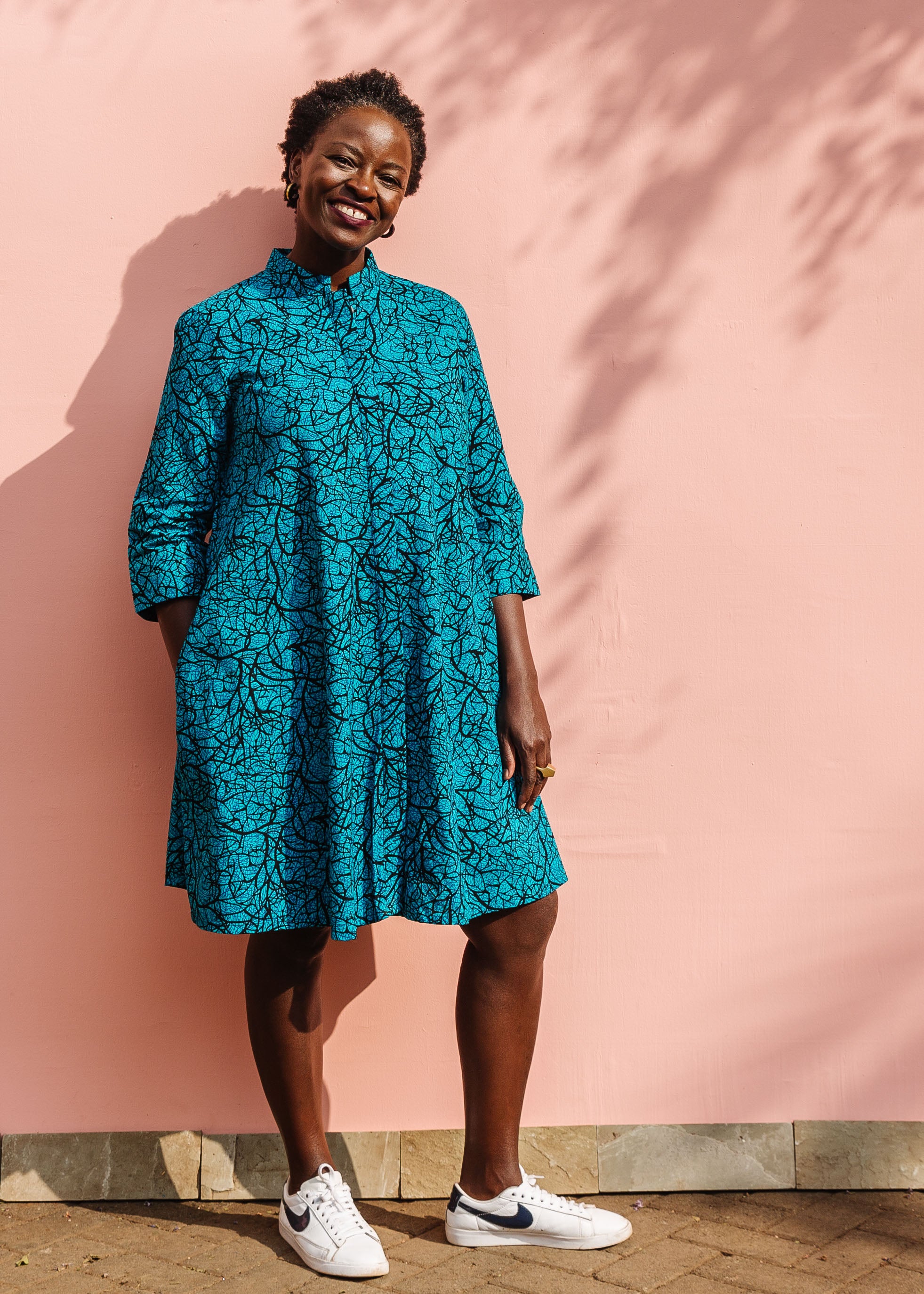 Model wearing blue dress with black abstract lines.