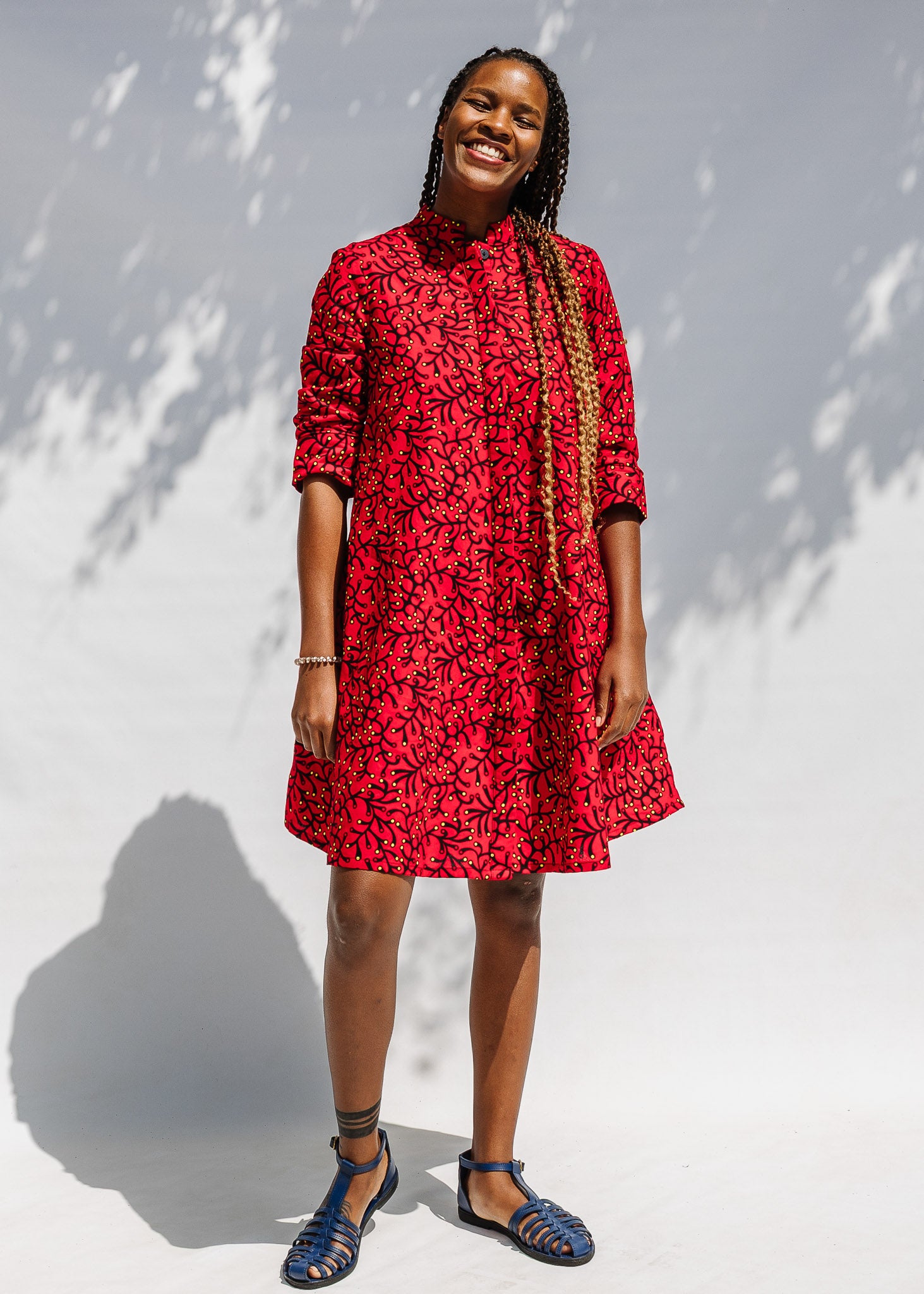 Model wearing red dress with small black and yellow branch design.