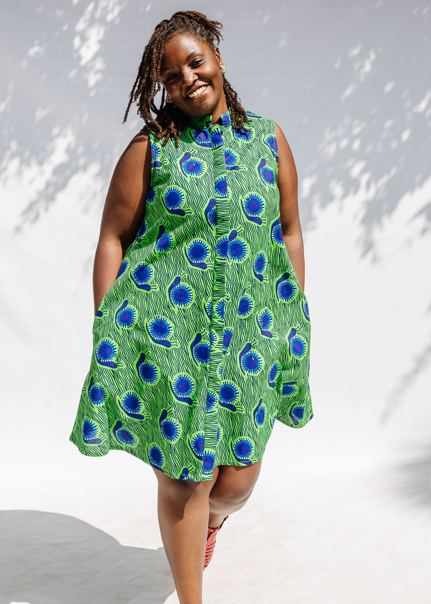 Model wearing sleeveless dress with green and blue snail print.