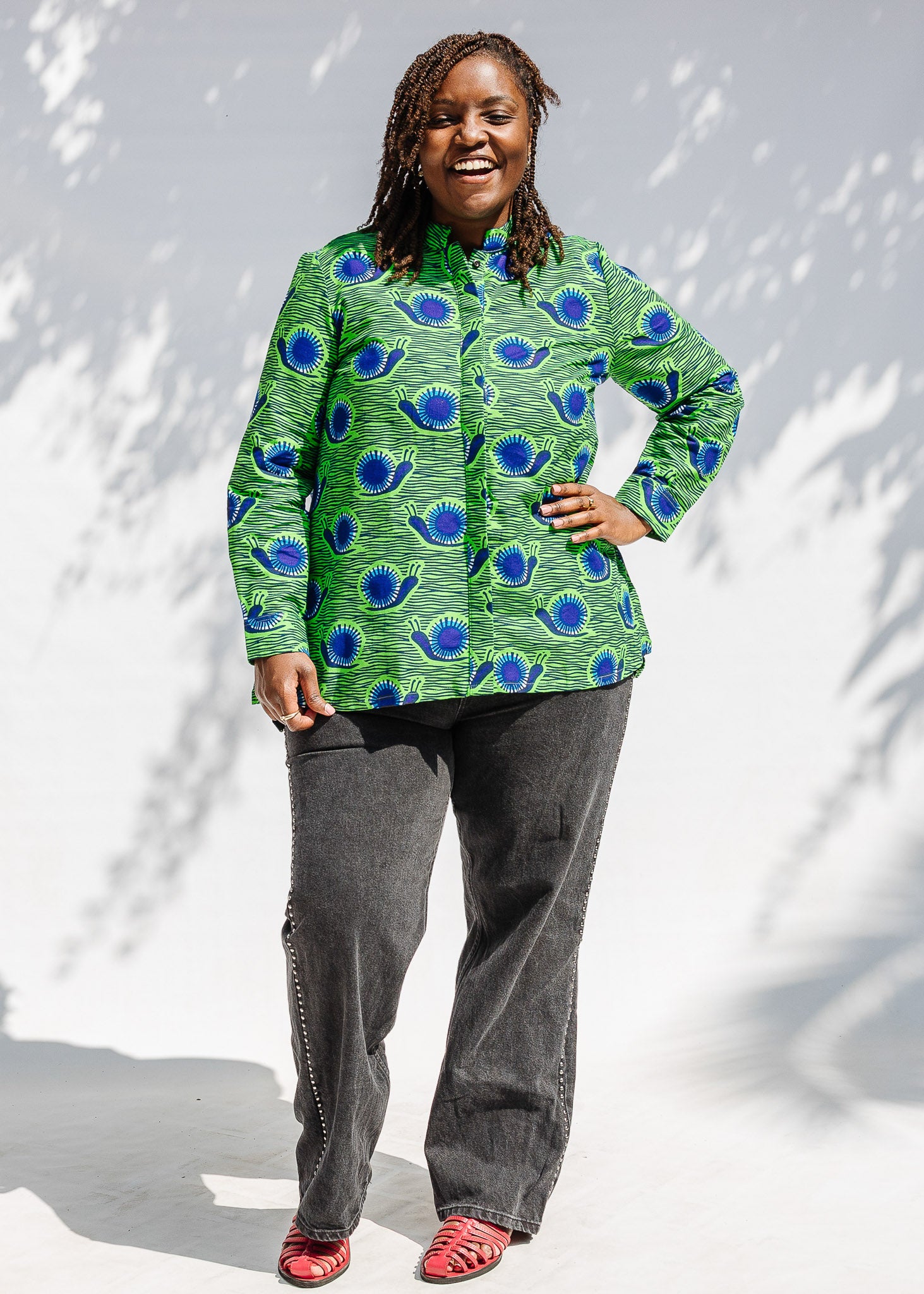 Model wearing green and blue snail print, long sleeved shirt.