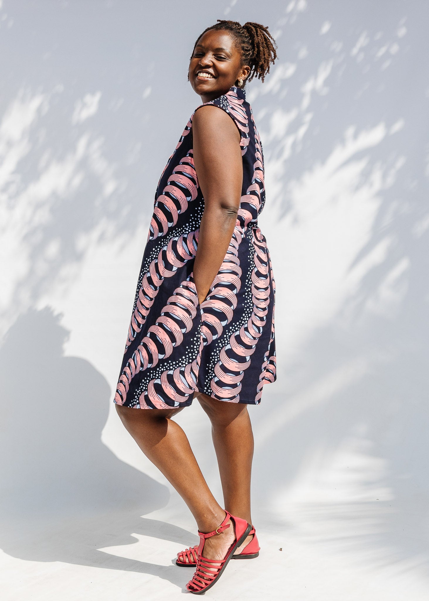 Model wearing black and pink sleeveless print dress.