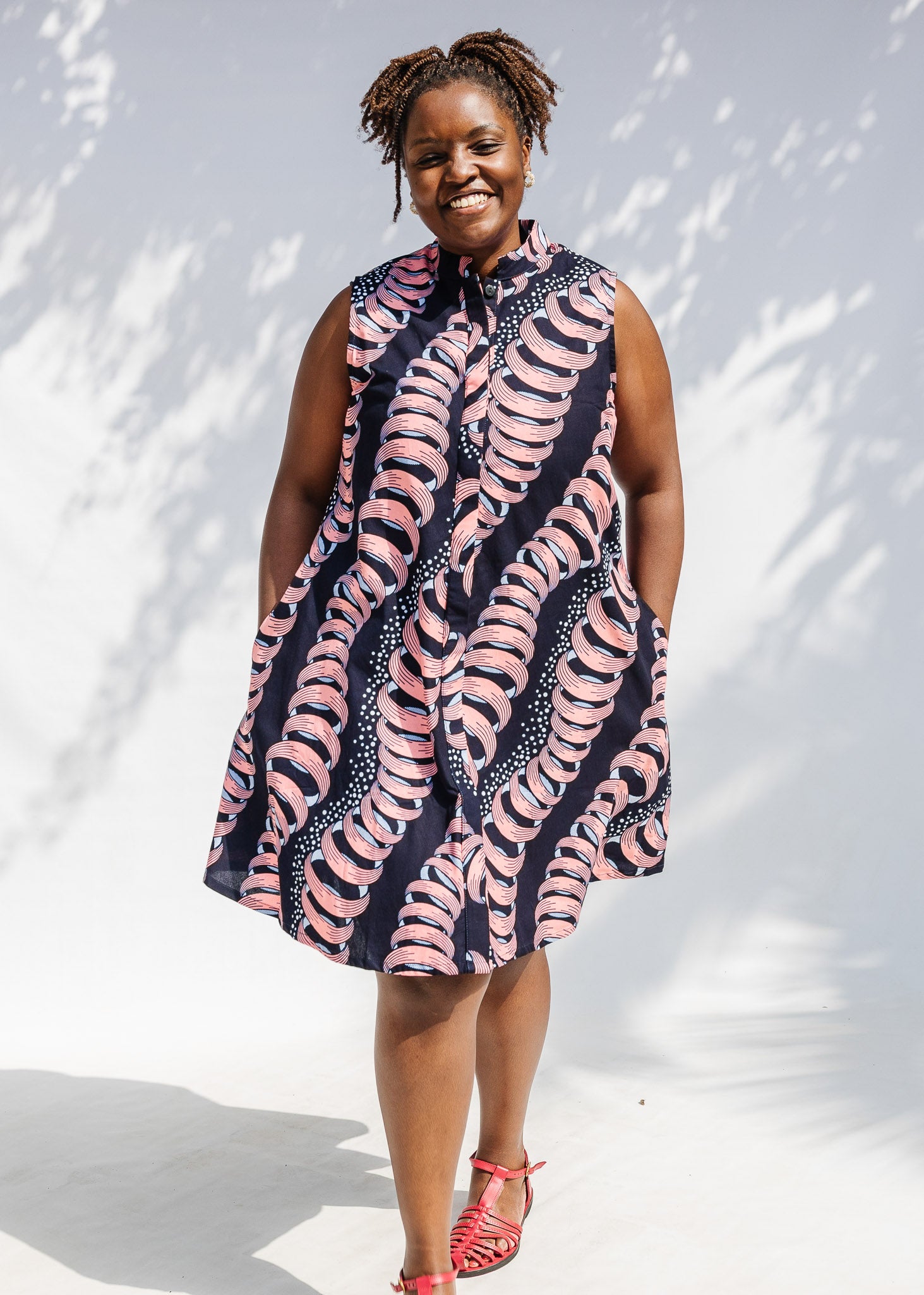 Model wearing black and pink sleeveless print dress.