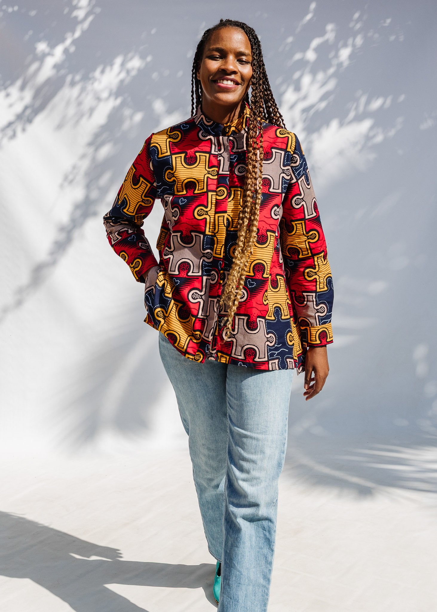 Model wearing multicolored puzzle print shirt.