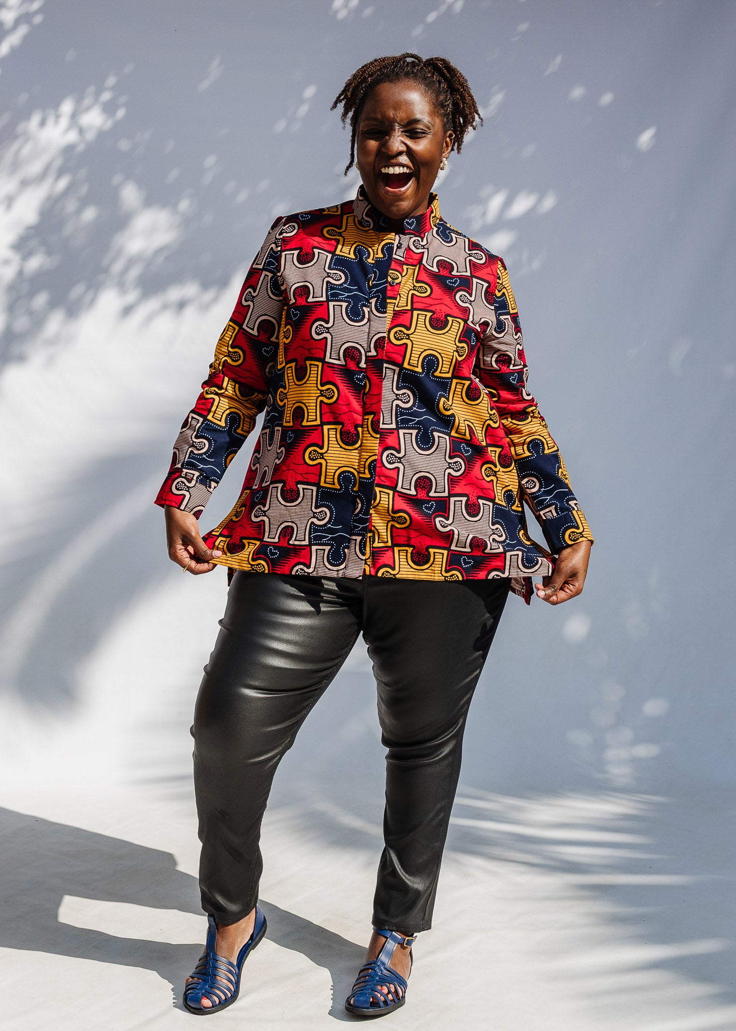 Model wearing multicolored puzzle print shirt.
