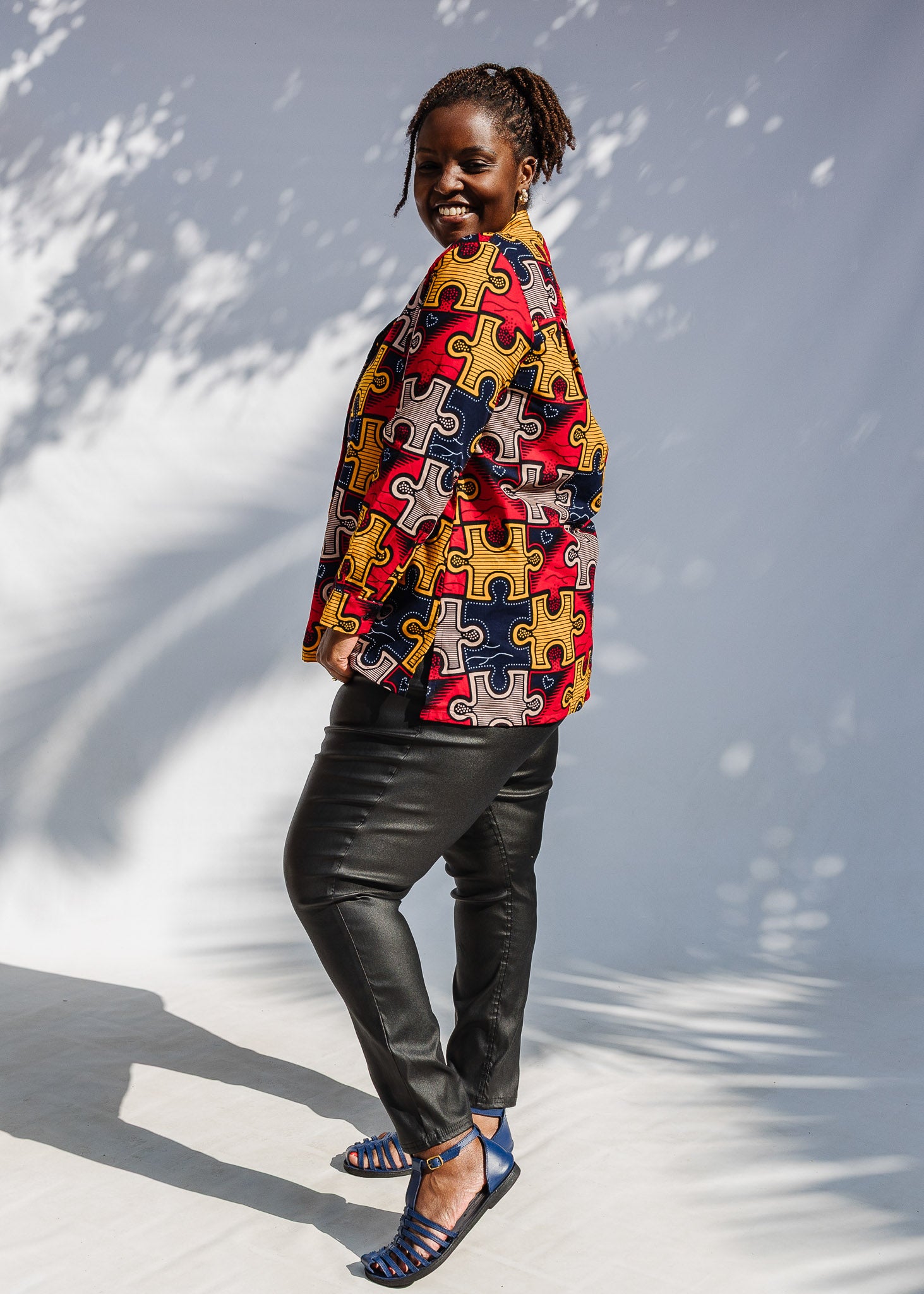 Model wearing multicolored puzzle print shirt.