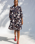 Model wearing black dress with pink and yellow floral print.