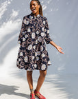 Model wearing black dress with pink and yellow floral print.
