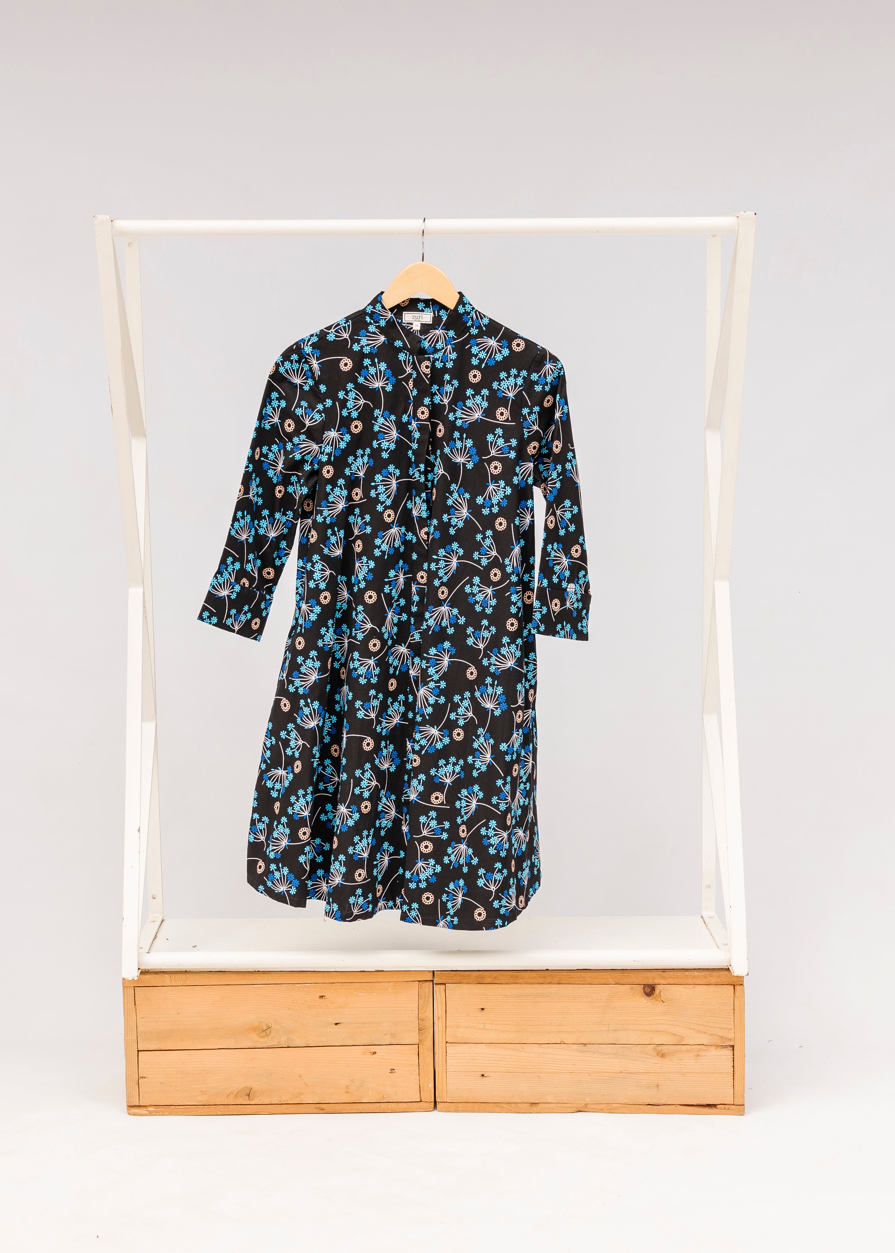 Display of black dress with blue and beige floral print.