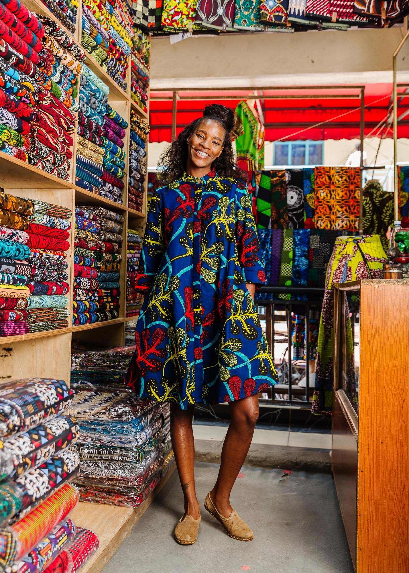 The model is wearing blue, red, yellow, black and aqua vine print dress