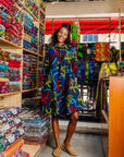 The model is wearing blue, red, yellow, black and aqua vine print dress