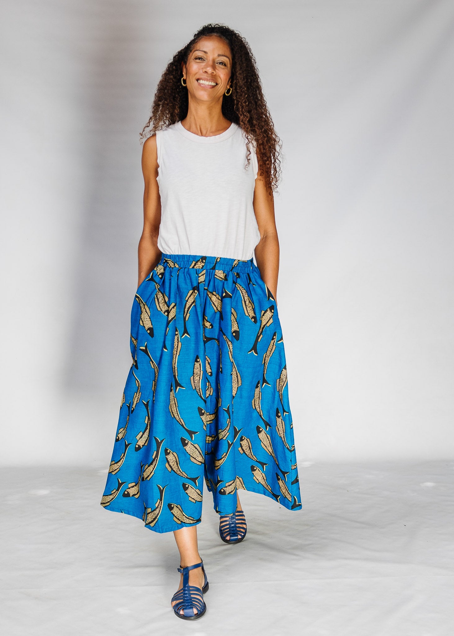Model wearing white shirt with blue pants with beige fish print.