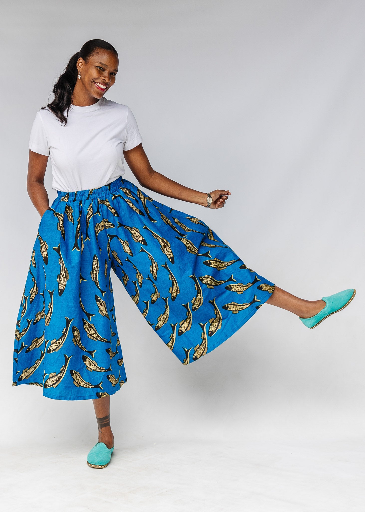 Model wearing white shirt with blue pants with beige fish print.