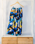 Display of blue, black, orange, yellow, orange and white geometric print shirt and culotte.