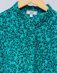 Display of turquoise dress with small black vine print.