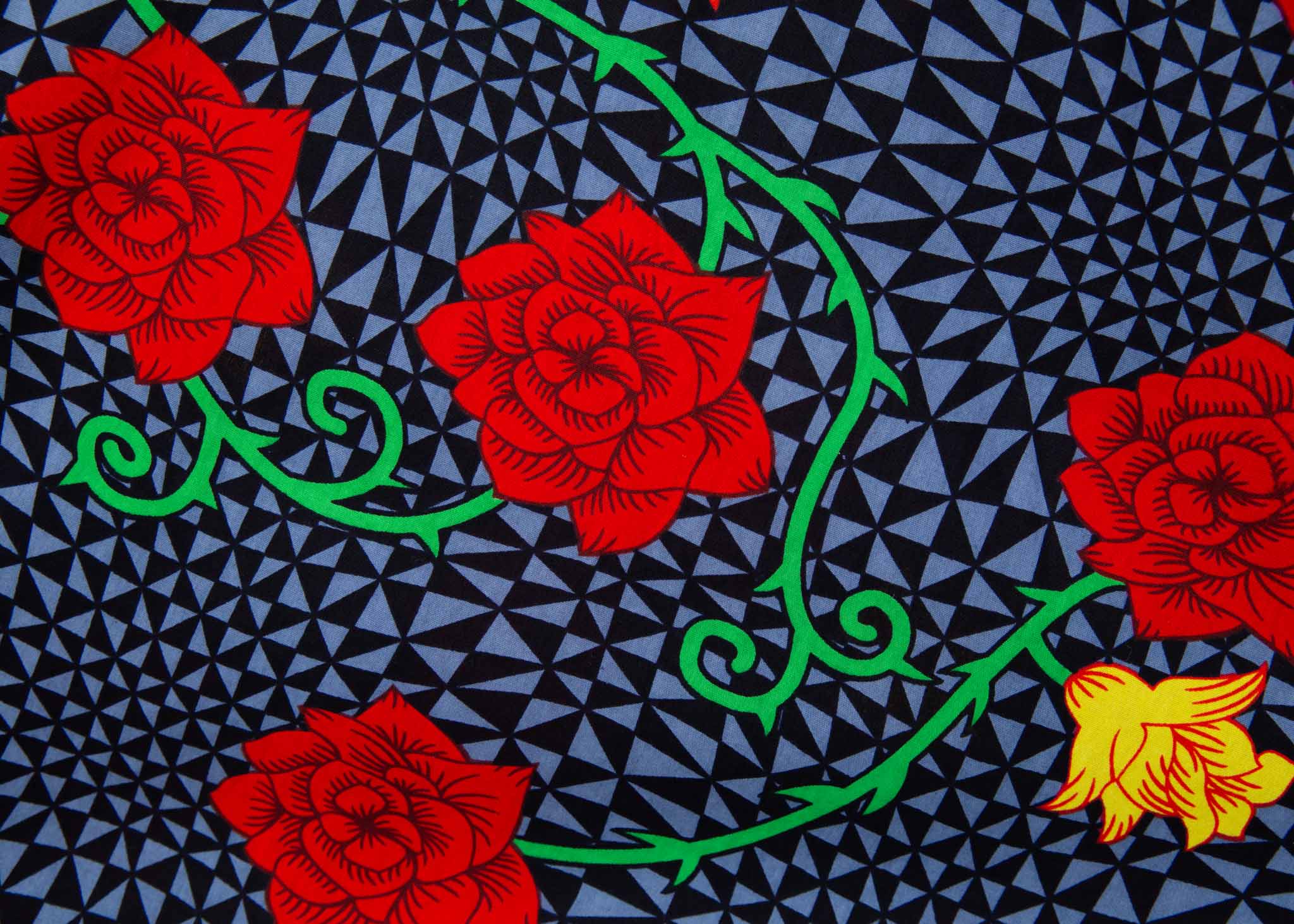 Close up Display of gray and black dress with yellow and red rose print, fabric.