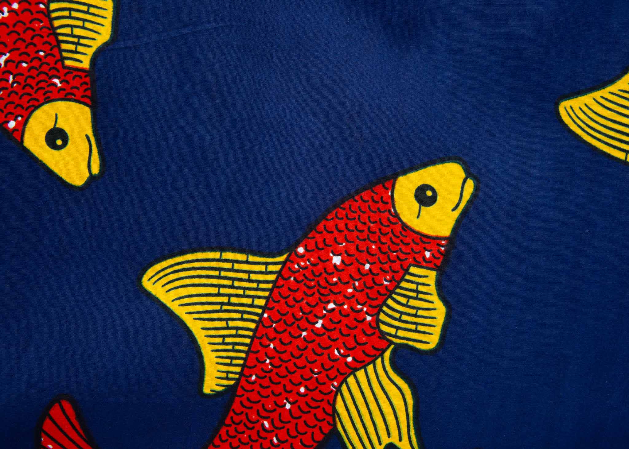 Close up display of navy sleeveless dress with red and yellow fish print.