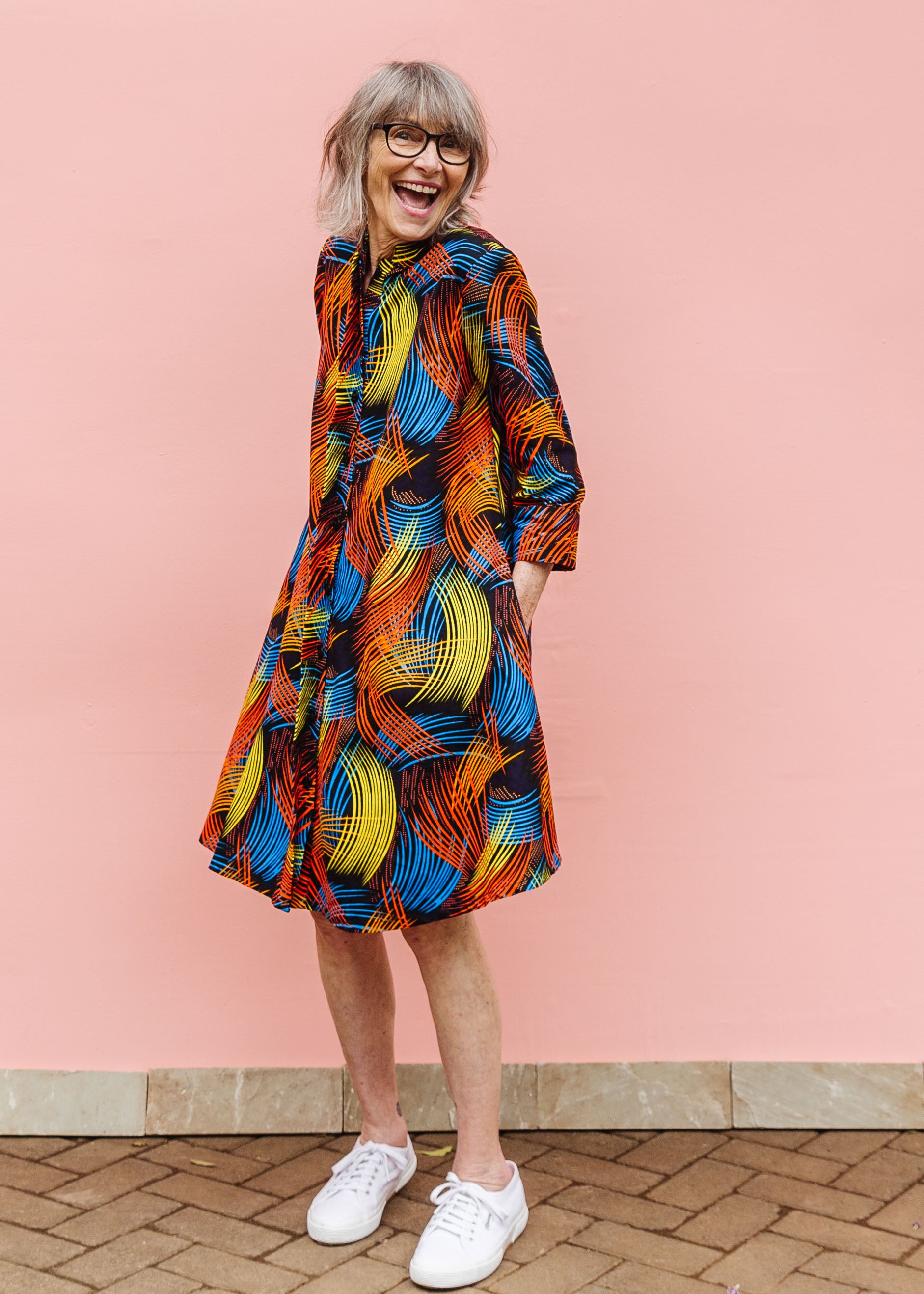 Model wearing black dress with rainbow brushstroke print.