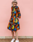 Model wearing black dress with rainbow brushstroke print.