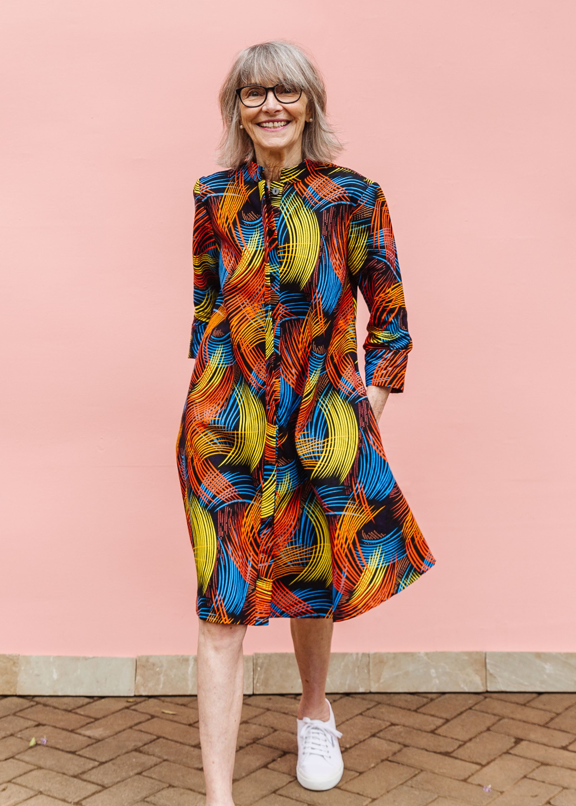 Model wearing black dress with rainbow brushstroke print.