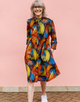 Model wearing black dress with rainbow brushstroke print.