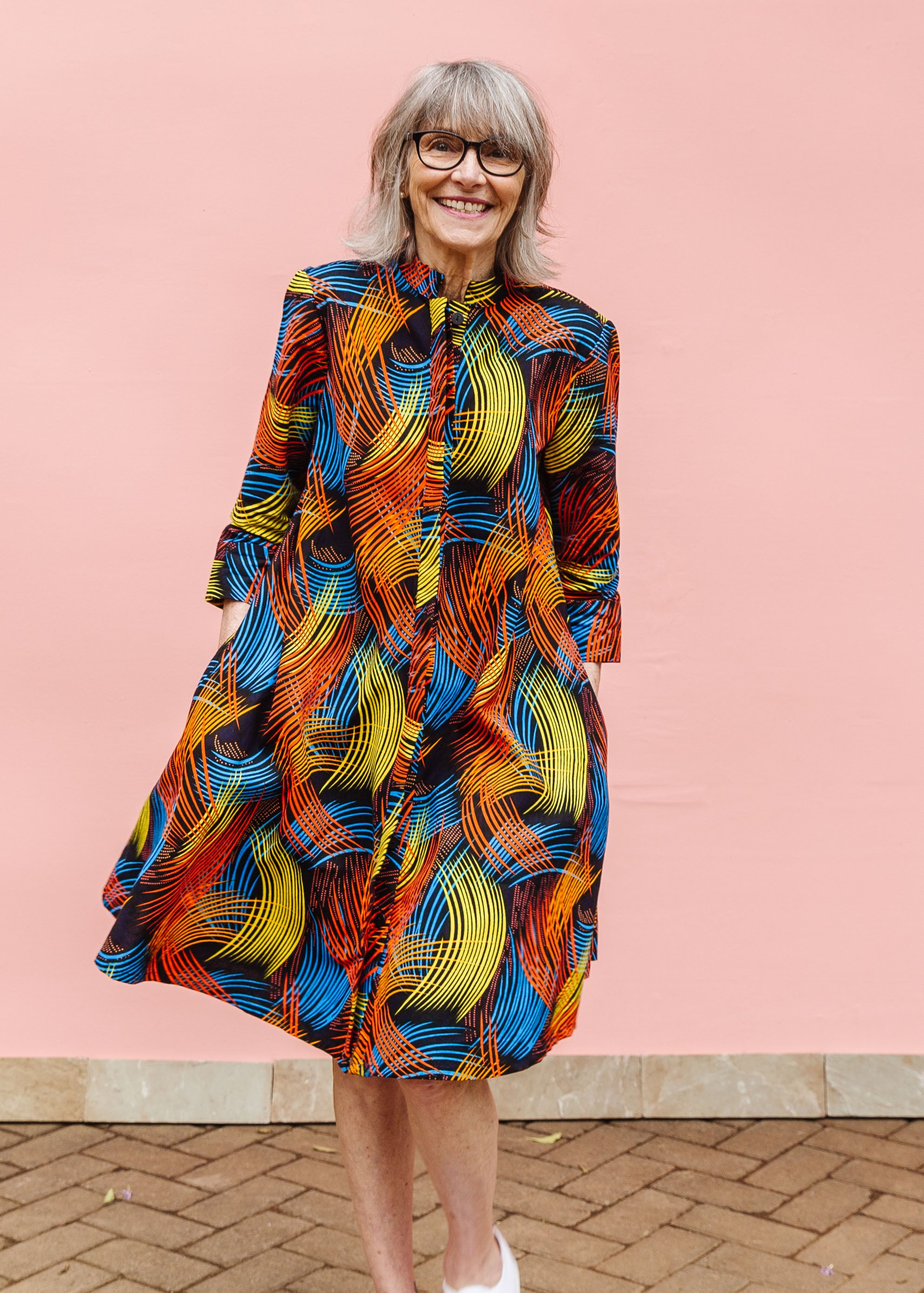 Model wearing black dress with rainbow brushstroke print.