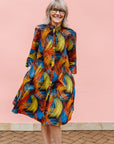 Model wearing black dress with rainbow brushstroke print.