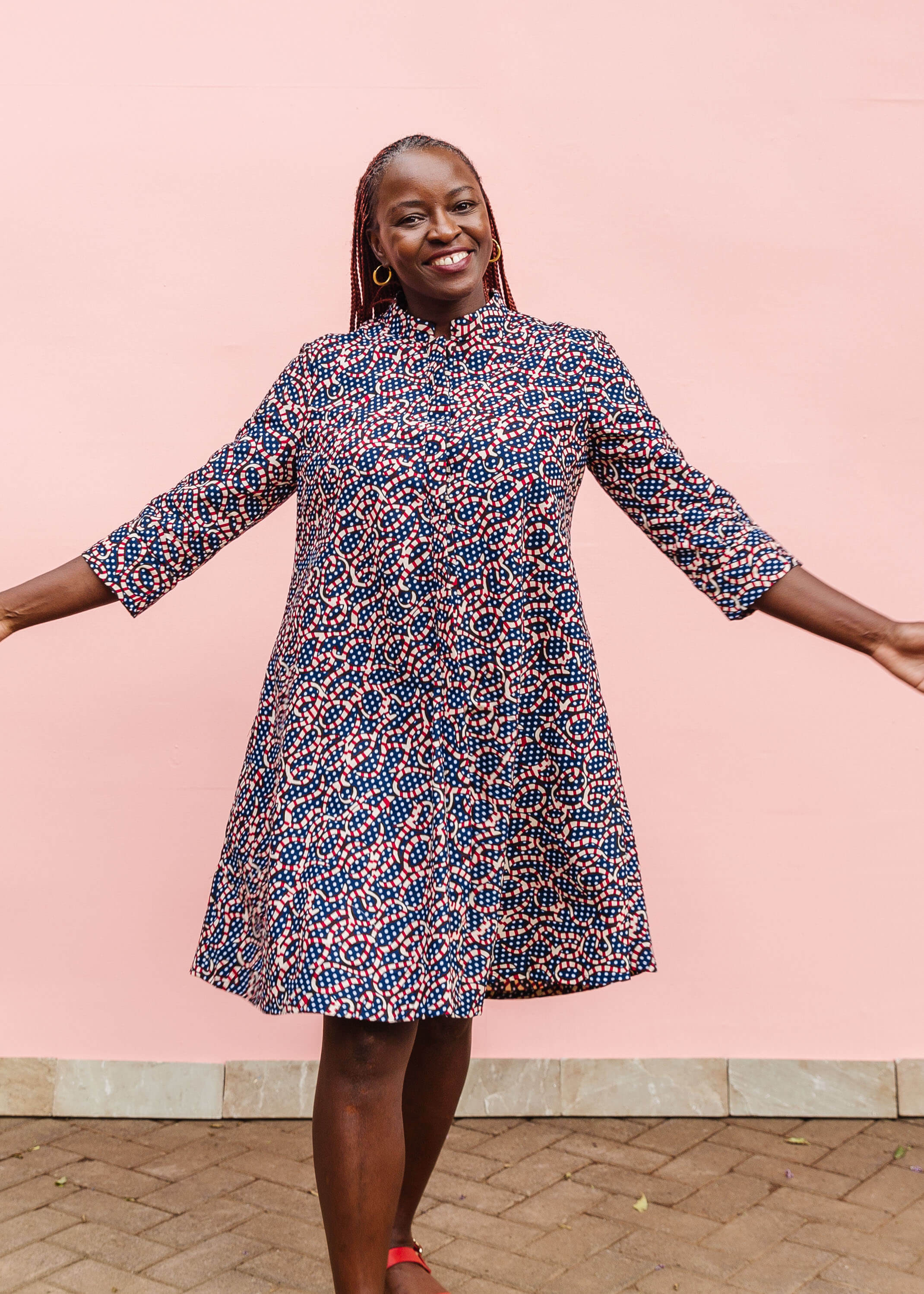 Model wearing blue and red ribbon print dress.