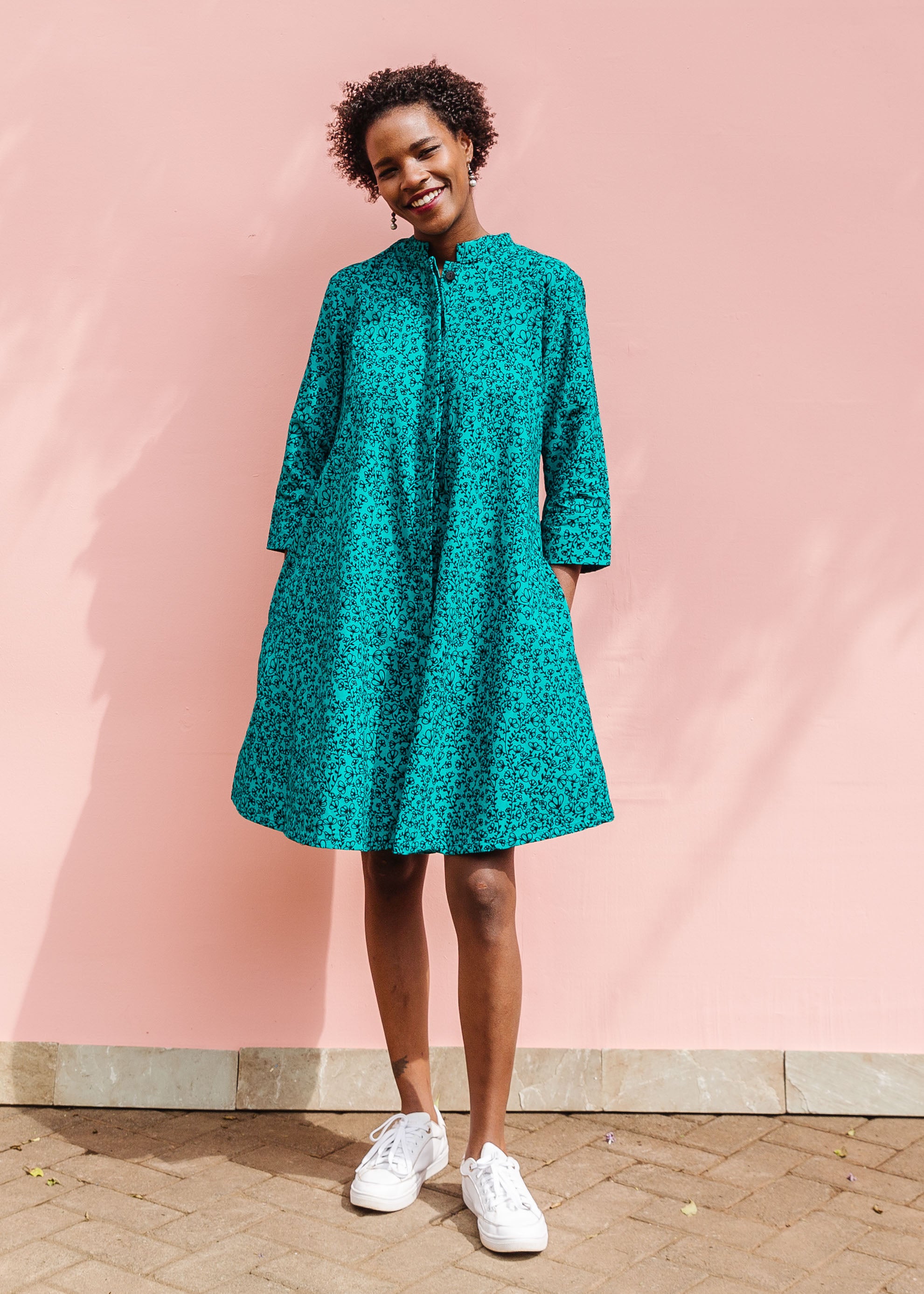 Model wearing turquoise dress with small black vine print.