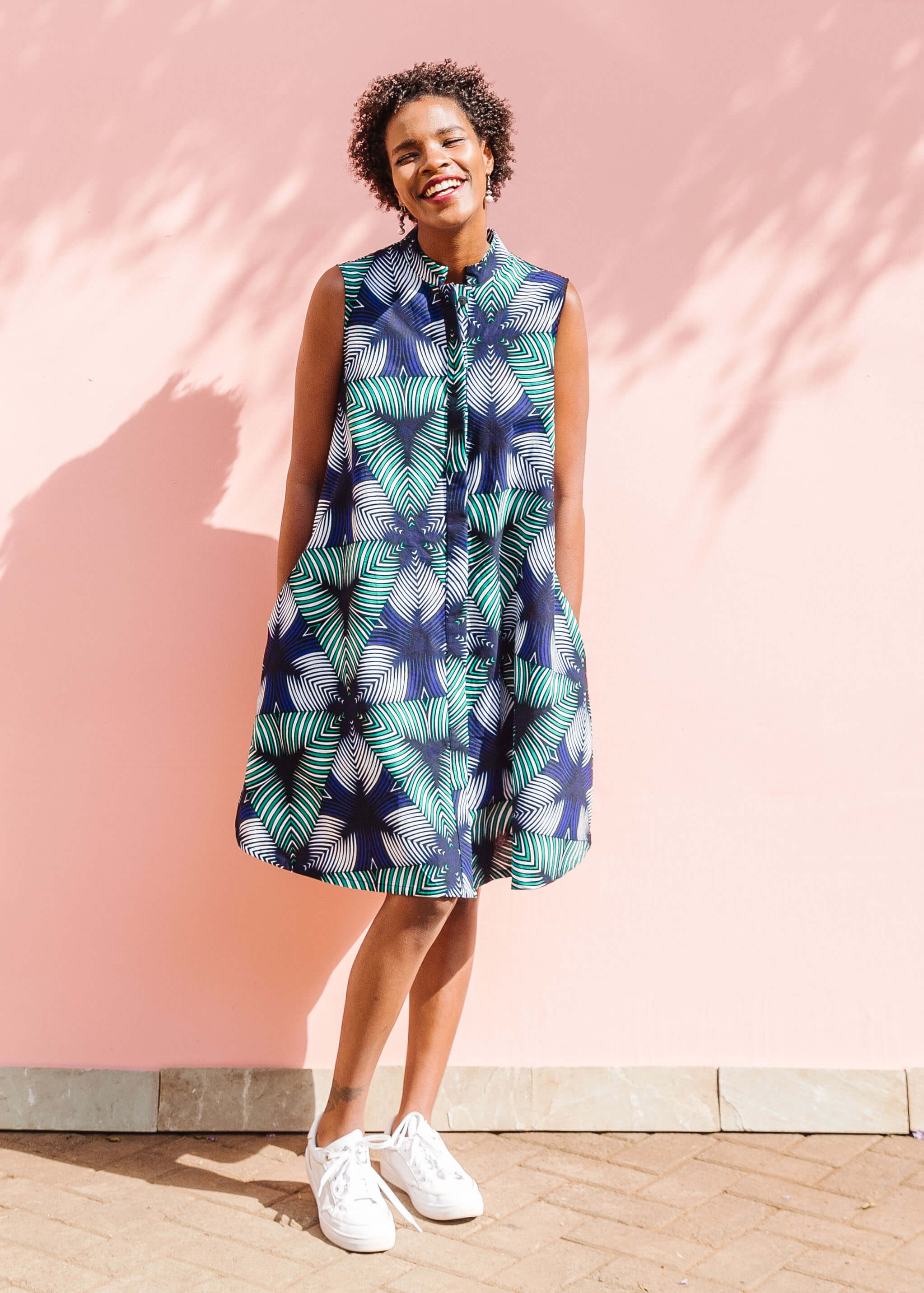 Model wearing blue, white, and green, geometric print dress.