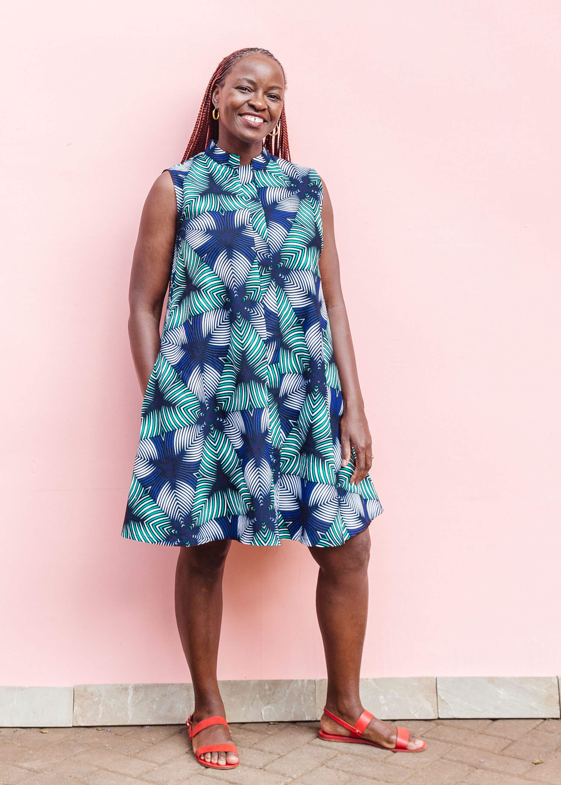 Model wearing blue, white, and green, geometric print dress.