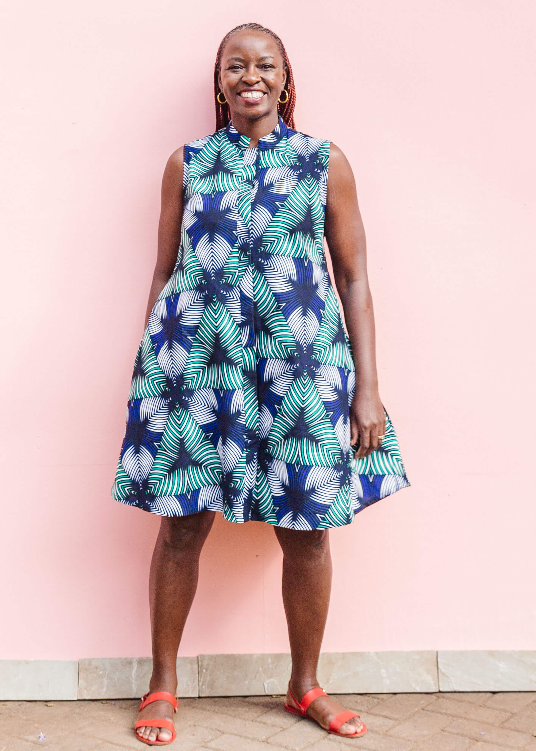 Model wearing blue, white, and green, geometric print dress.