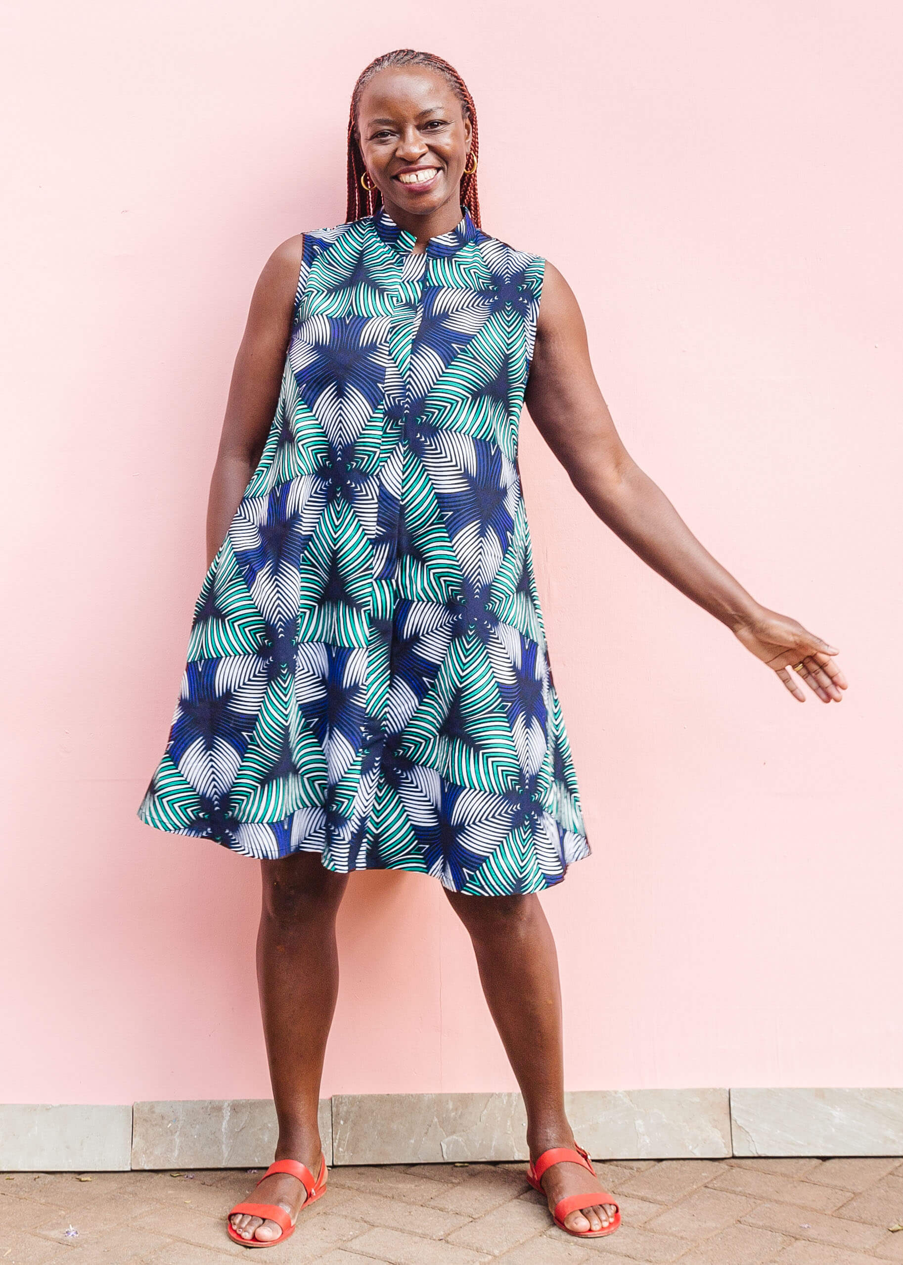 Model wearing blue, white, and green, geometric print dress.