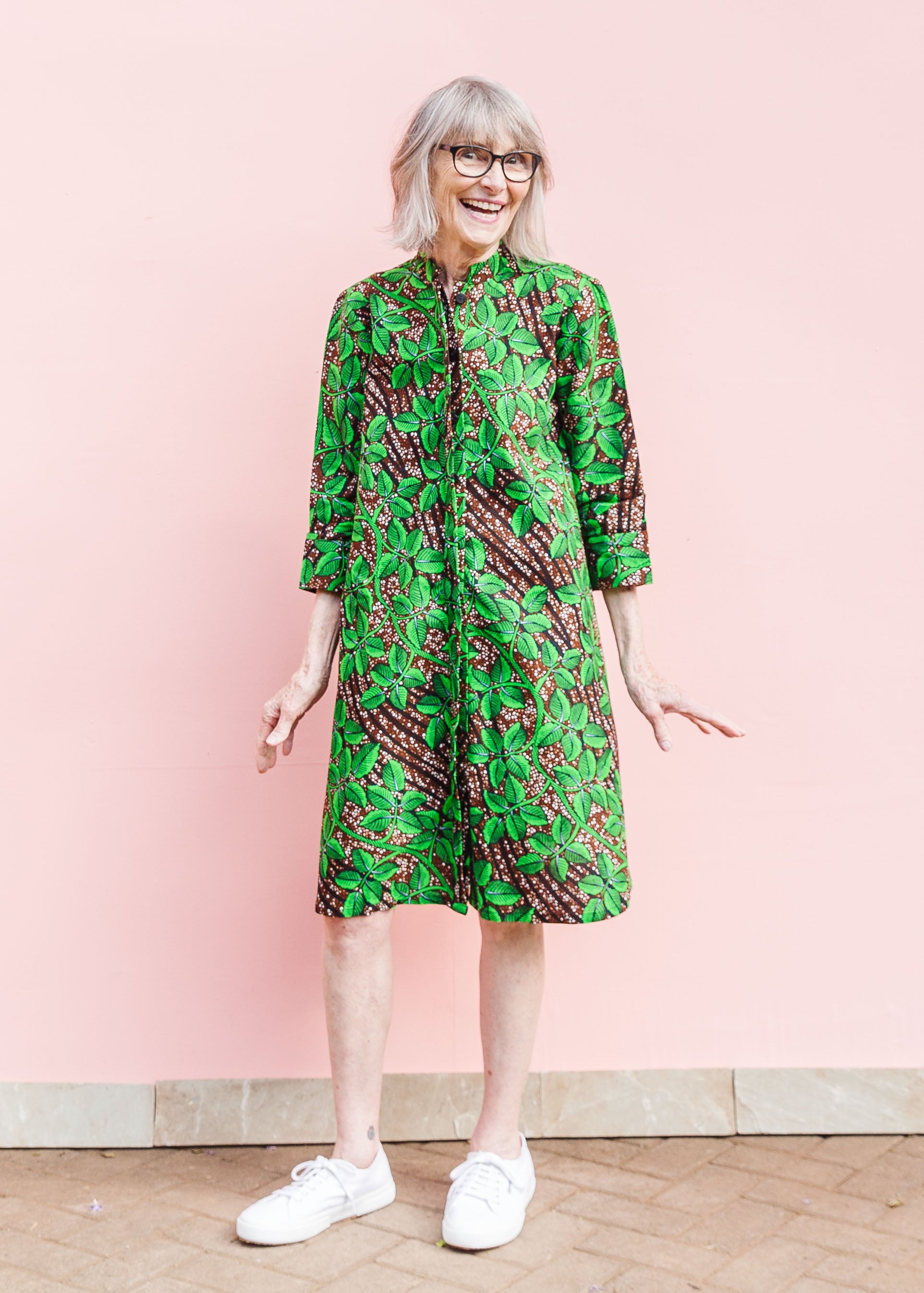 Model wearing brown dress with green vine print.