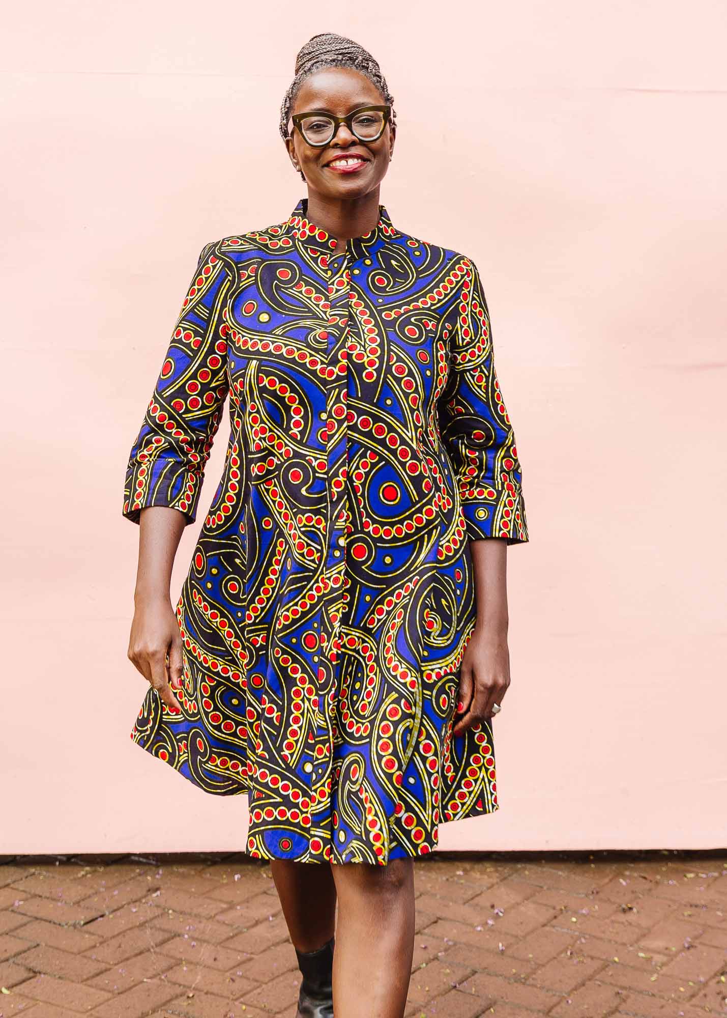 The model is wearing blue, red, black, yellow and white ornamental print dress 
