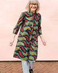 The model is wearing multicolored leaf print dress