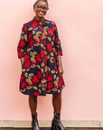 The model is wearing navy dress with red, white and orange floral print