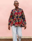 The model is wearing navy shirt with red, orange, yellow and white geometric print 
