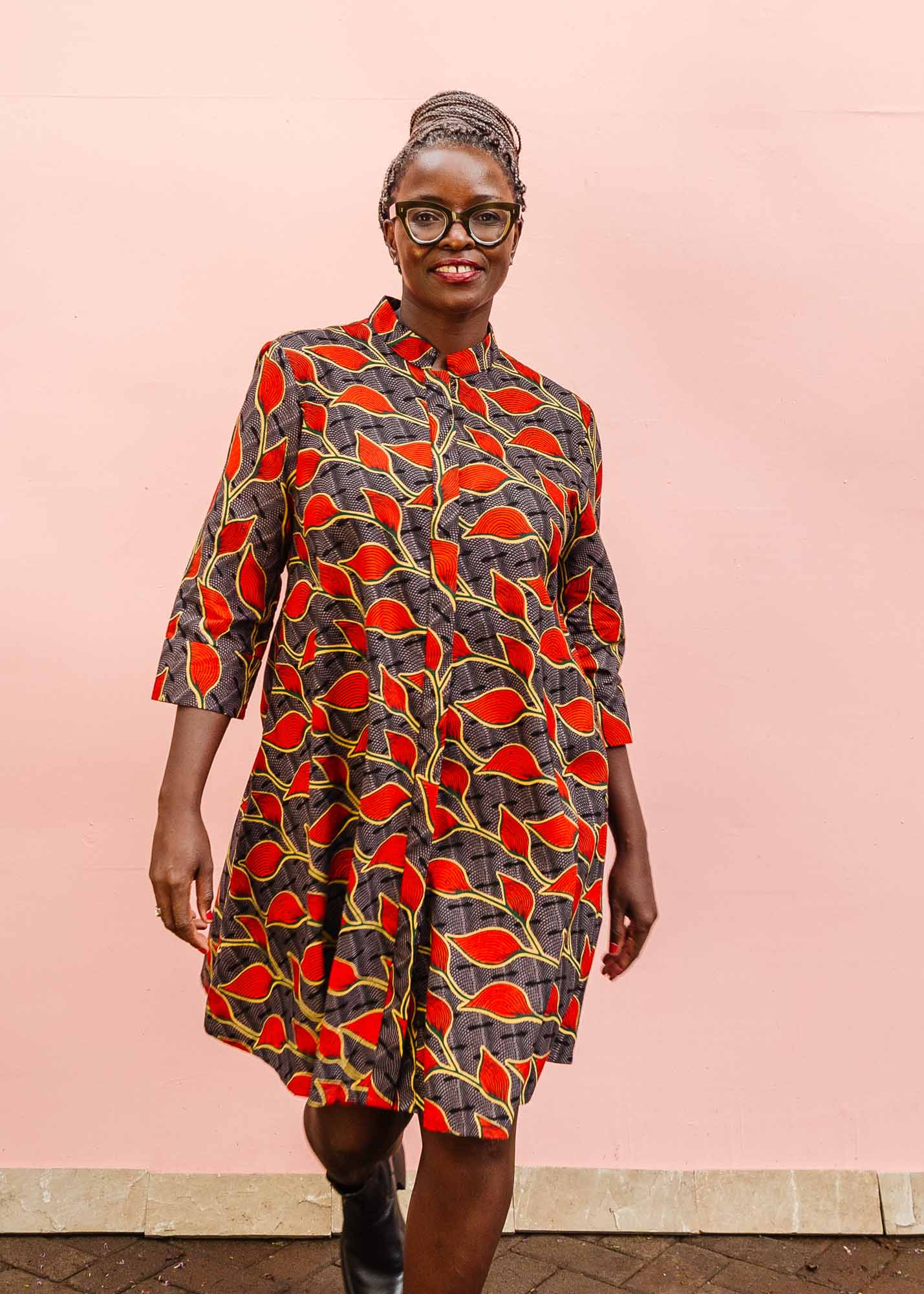 The model is wearing grey dress with red, yellow and black leaf print