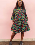 The model is wearing multicolored leaf print dress