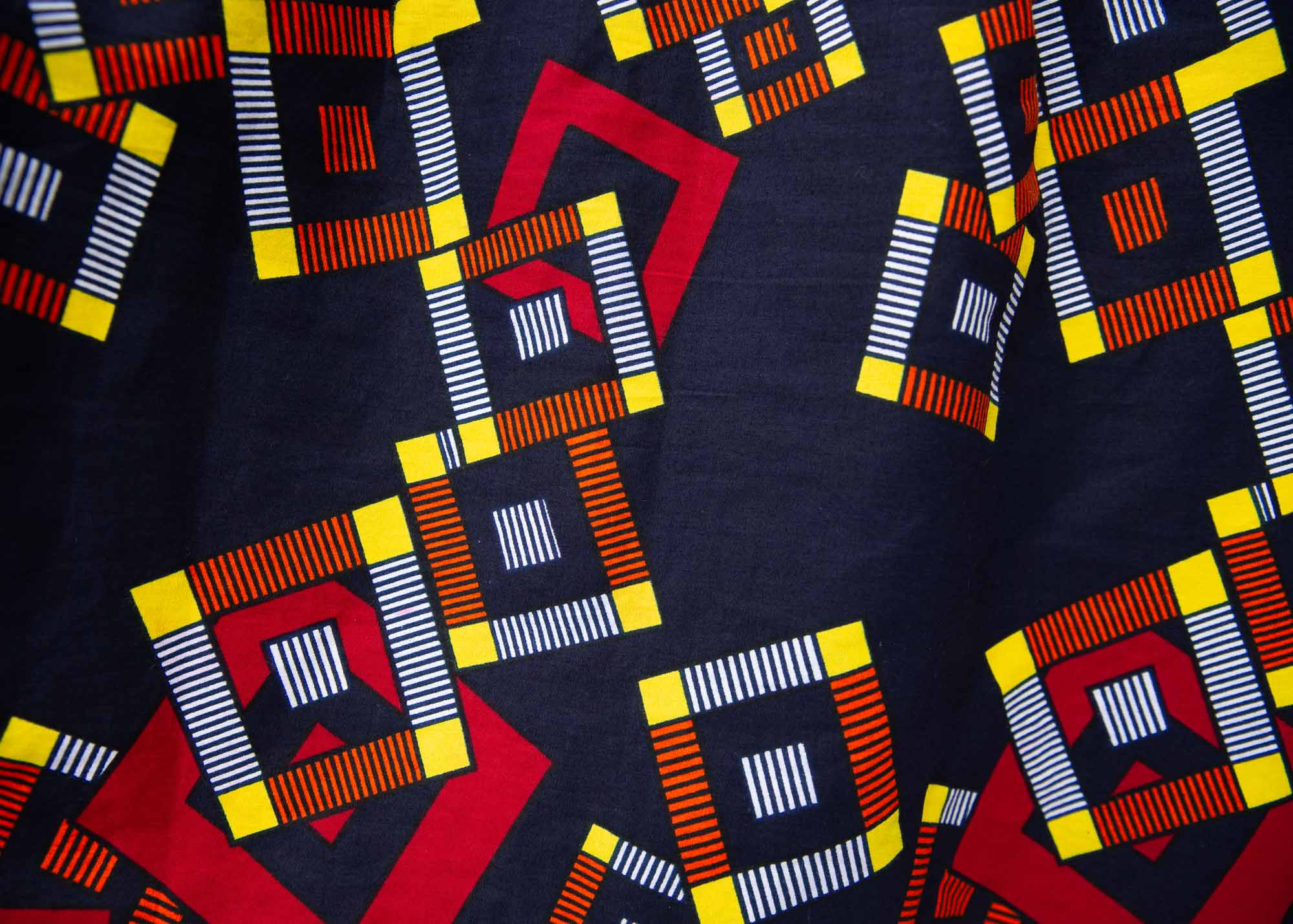 Close up of navy shirt with red, orange, yellow and white geometric print, fabric