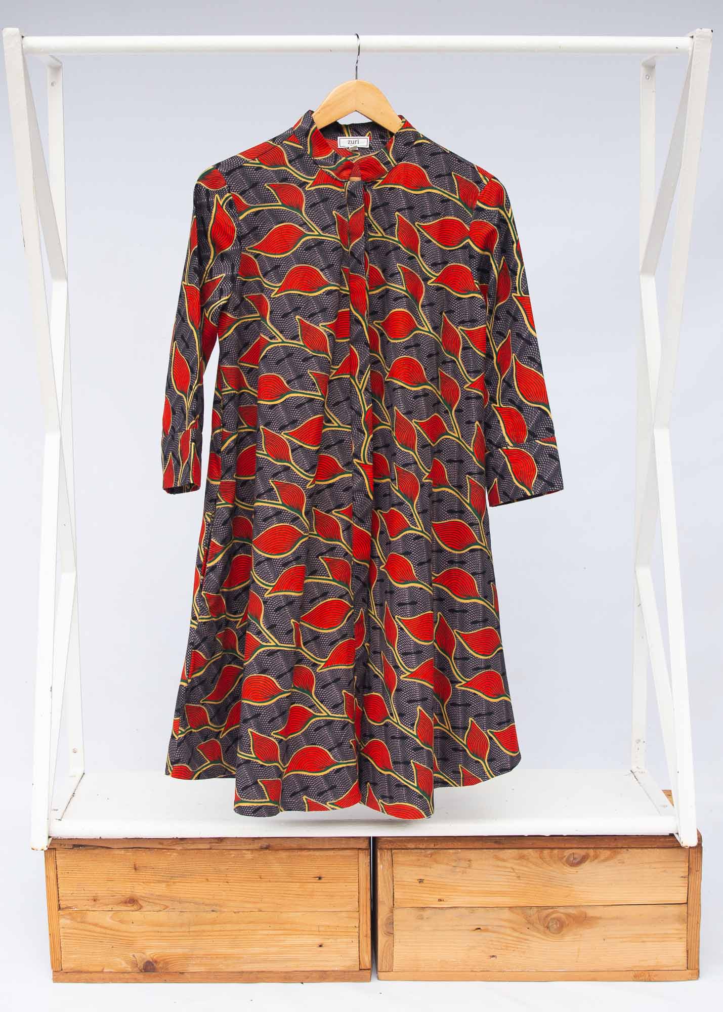 Display of grey dress with red, yellow and black leaf print