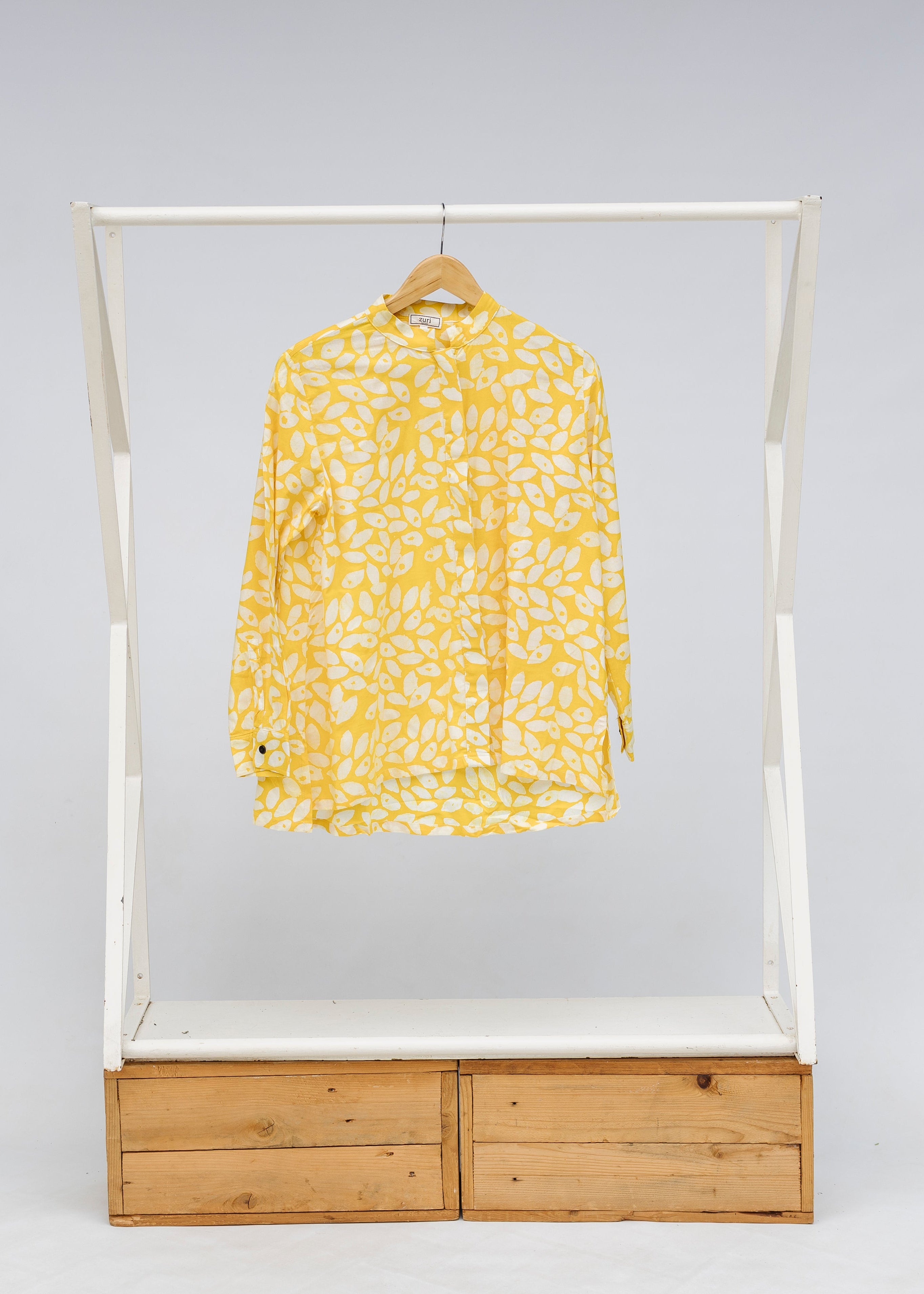 Display of yellow long sleeve shirt with white leaf print.